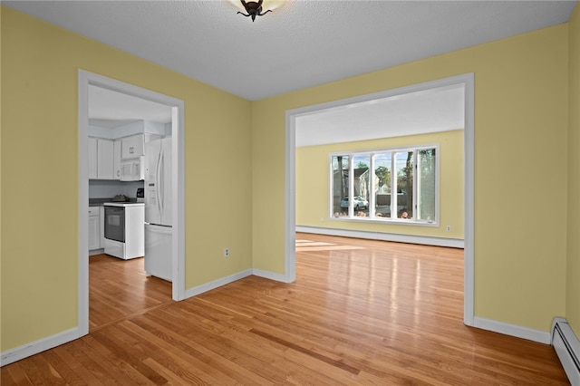 unfurnished room featuring a baseboard radiator, a textured ceiling, and light wood-type flooring