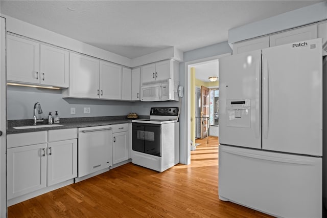 kitchen with a textured ceiling, white appliances, sink, light hardwood / wood-style floors, and white cabinetry