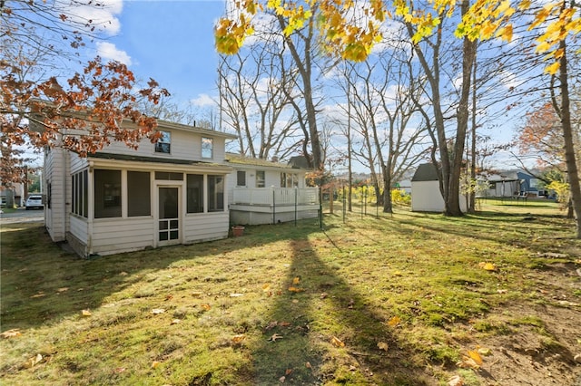 back of property with a sunroom, a storage unit, and a lawn