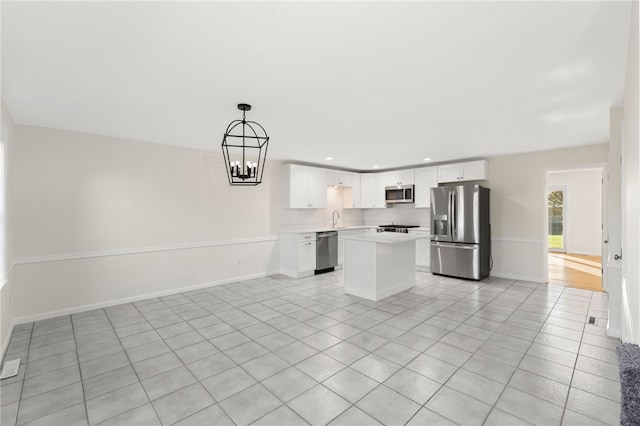 kitchen with a center island, stainless steel appliances, backsplash, decorative light fixtures, and white cabinets