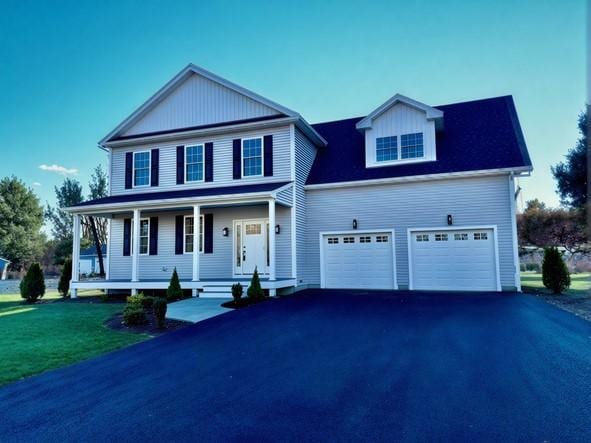 view of front of house with a porch, a garage, and a front lawn