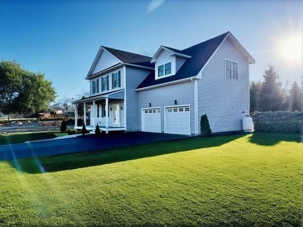 back of house featuring a porch, a garage, and a yard