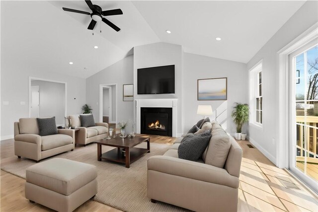 living room with ceiling fan, vaulted ceiling, and light wood-type flooring