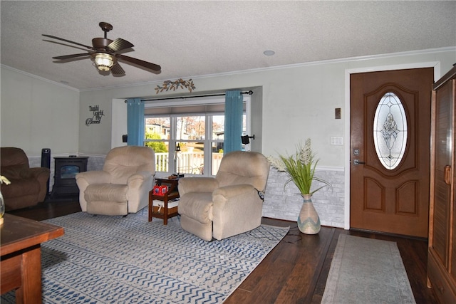 living room with wood-type flooring, a wood stove, a textured ceiling, and ornamental molding