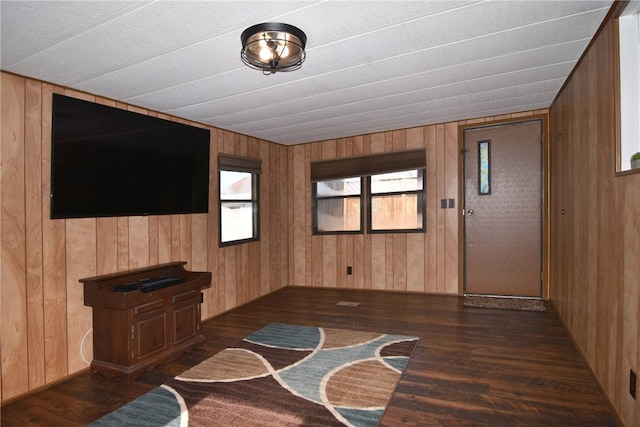 unfurnished living room with wooden walls and dark hardwood / wood-style floors