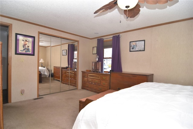 bedroom with carpet flooring, ornamental molding, a textured ceiling, ceiling fan, and a closet