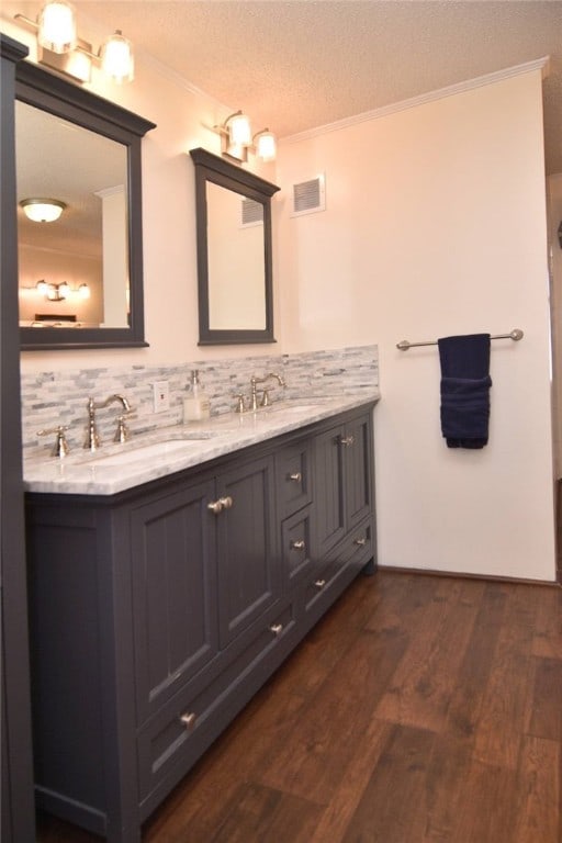 bathroom with backsplash, vanity, a textured ceiling, crown molding, and hardwood / wood-style floors