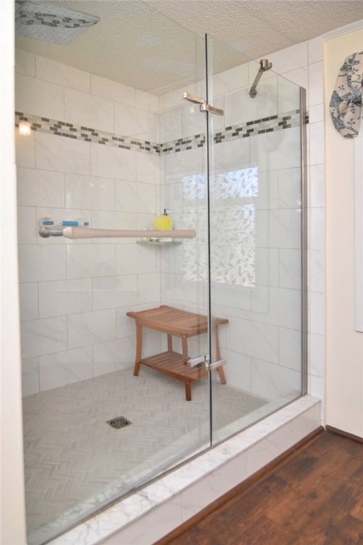 bathroom featuring hardwood / wood-style floors, a tile shower, and a textured ceiling