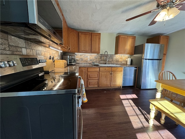 kitchen featuring sink, dark wood-type flooring, tasteful backsplash, a textured ceiling, and appliances with stainless steel finishes