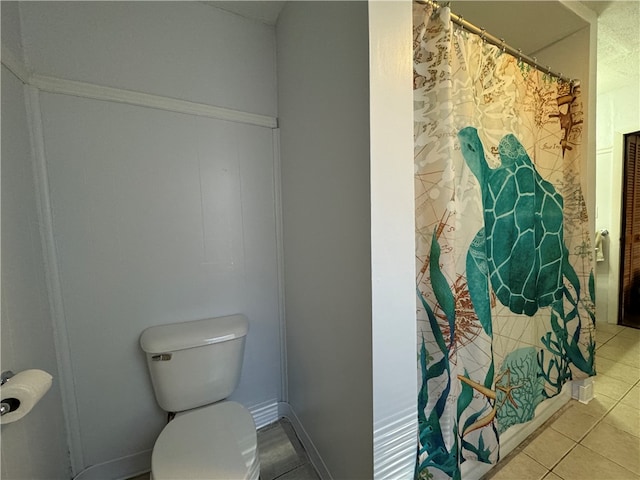 bathroom with tile patterned floors, curtained shower, and toilet