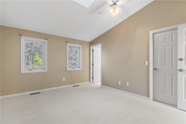 spare room featuring light colored carpet, lofted ceiling with skylight, and ceiling fan