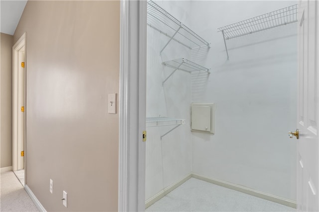 walk in closet with light colored carpet and vaulted ceiling