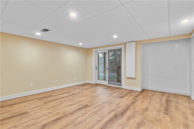 spare room with a paneled ceiling and light hardwood / wood-style flooring