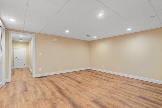 spare room with light hardwood / wood-style flooring and a drop ceiling