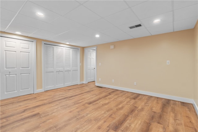 basement with a paneled ceiling and light wood-type flooring