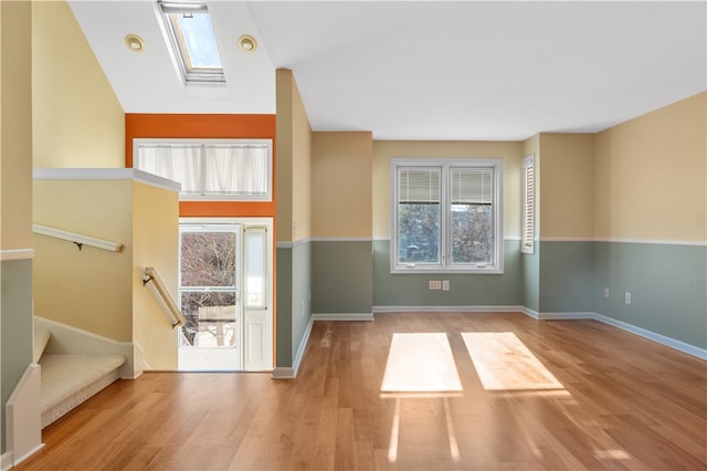 interior space with lofted ceiling with skylight, plenty of natural light, and light hardwood / wood-style floors