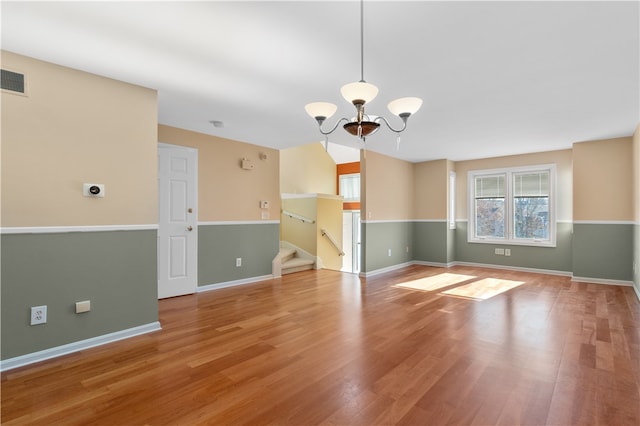 spare room with a notable chandelier and wood-type flooring