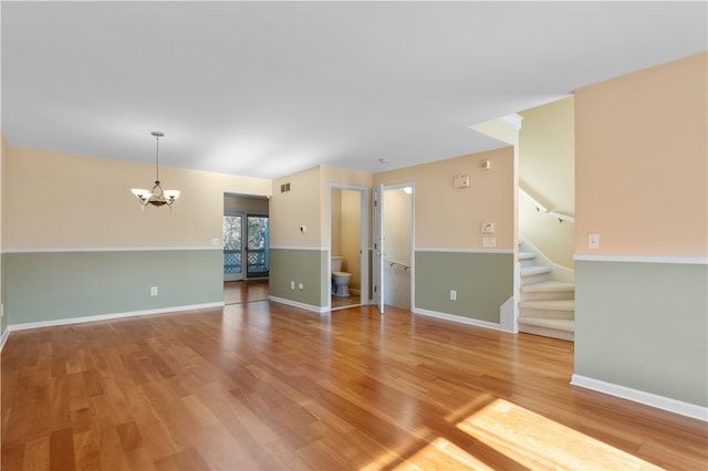 unfurnished room featuring hardwood / wood-style floors and a chandelier