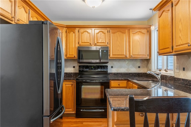 kitchen with kitchen peninsula, appliances with stainless steel finishes, light wood-type flooring, backsplash, and sink