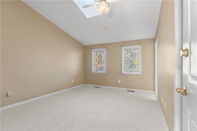 carpeted empty room with vaulted ceiling with skylight and ceiling fan