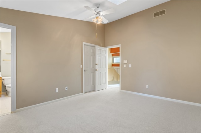 spare room featuring light carpet, a skylight, and ceiling fan