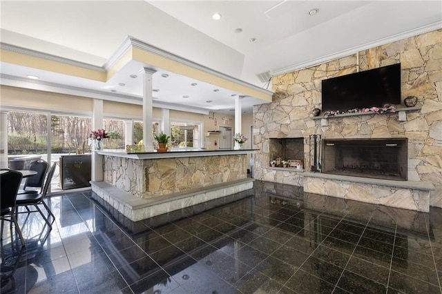 interior space featuring ornate columns, a stone fireplace, a healthy amount of sunlight, and crown molding