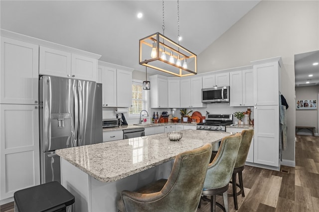 kitchen featuring white cabinetry, a center island, pendant lighting, a breakfast bar, and appliances with stainless steel finishes