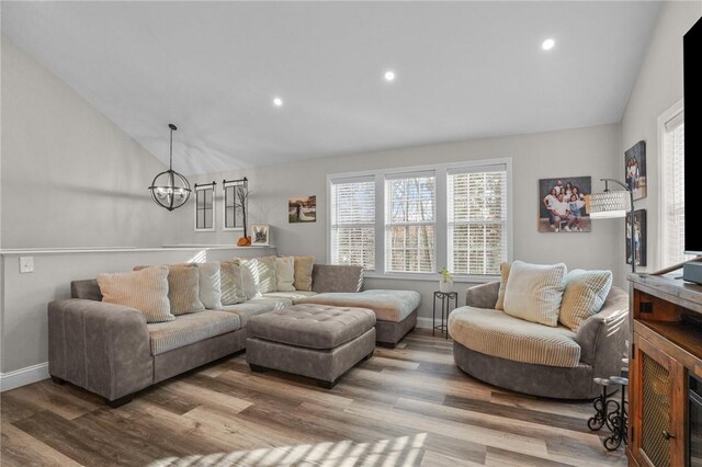 living room featuring hardwood / wood-style floors, lofted ceiling, and a notable chandelier