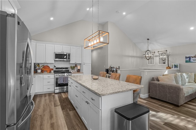 kitchen featuring white cabinetry, a center island, hanging light fixtures, stainless steel appliances, and decorative backsplash