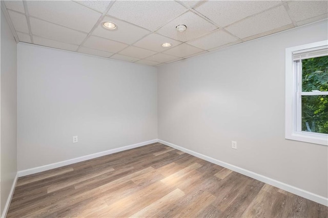 spare room featuring wood-type flooring and a drop ceiling