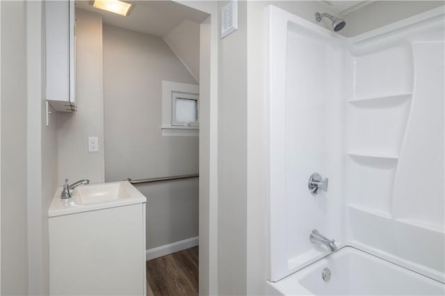 bathroom featuring hardwood / wood-style floors, vanity, vaulted ceiling, and tub / shower combination