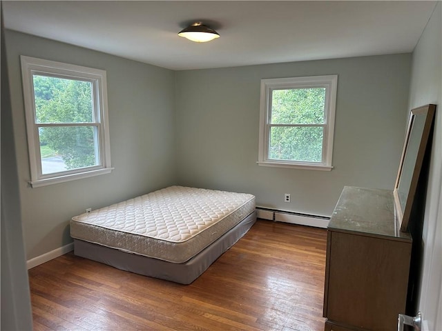 bedroom featuring dark hardwood / wood-style flooring, multiple windows, and a baseboard radiator