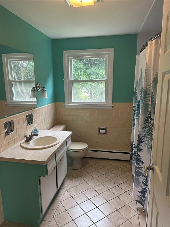 bathroom with tile patterned floors, toilet, vanity, and a baseboard heating unit