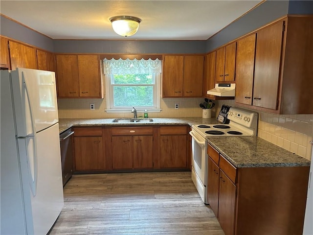 kitchen featuring white appliances, dark stone counters, sink, decorative backsplash, and light wood-type flooring