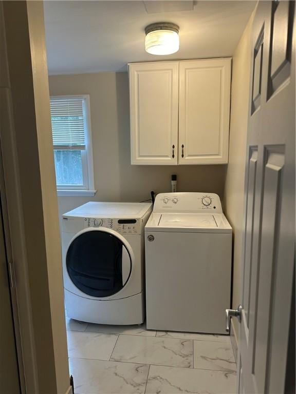 clothes washing area with washing machine and clothes dryer and cabinets