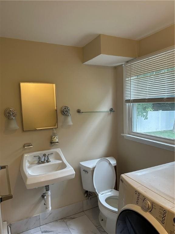 bathroom featuring toilet, washer / dryer, and sink