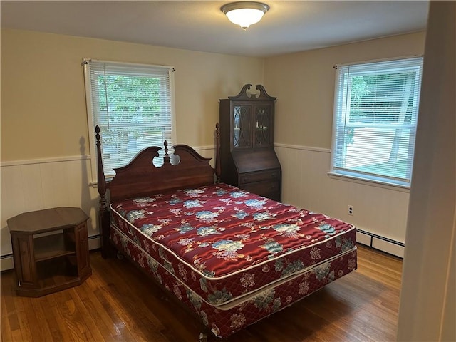 bedroom with a baseboard radiator and hardwood / wood-style flooring