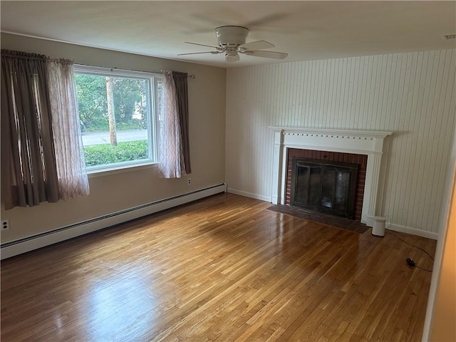 unfurnished living room featuring light hardwood / wood-style floors, ceiling fan, a baseboard radiator, and a brick fireplace