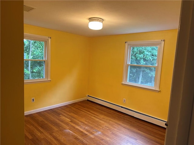 spare room featuring a healthy amount of sunlight, a baseboard radiator, and wood-type flooring