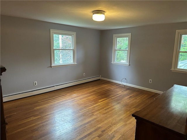 unfurnished room with dark hardwood / wood-style flooring and a baseboard heating unit