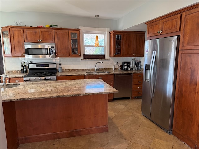 kitchen with light stone countertops, sink, hanging light fixtures, tasteful backsplash, and appliances with stainless steel finishes