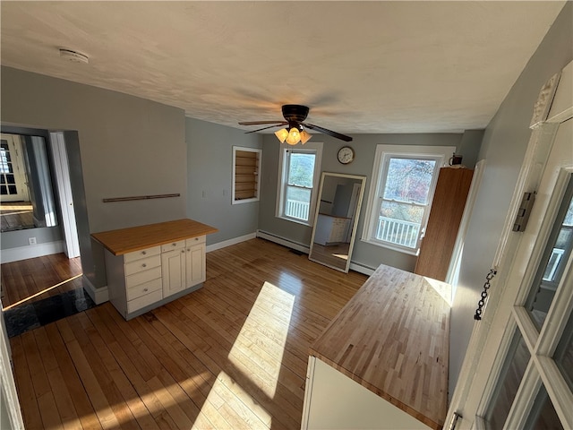 kitchen with ceiling fan, light hardwood / wood-style flooring, wooden counters, and a baseboard heating unit