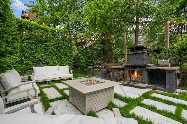 view of patio with an outdoor living space with a fireplace and an outdoor kitchen