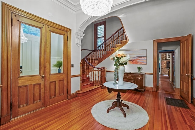 entrance foyer featuring crown molding, wood-type flooring, and a notable chandelier