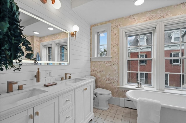 bathroom featuring tile patterned floors, a washtub, vanity, baseboard heating, and toilet