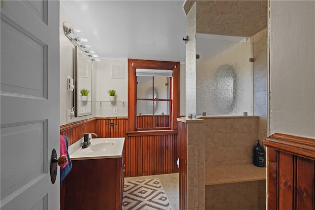 bathroom with a tile shower, vanity, tile patterned floors, and wood walls