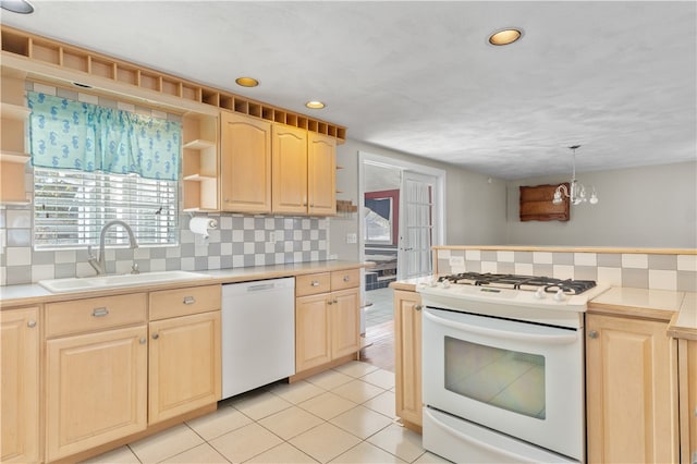 kitchen featuring white appliances, sink, light brown cabinets, pendant lighting, and an inviting chandelier