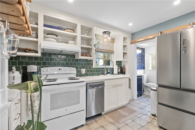 kitchen featuring a barn door, stainless steel appliances, white cabinetry, and a wealth of natural light