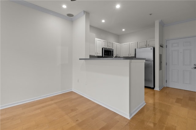 kitchen with crown molding, appliances with stainless steel finishes, light hardwood / wood-style floors, and kitchen peninsula