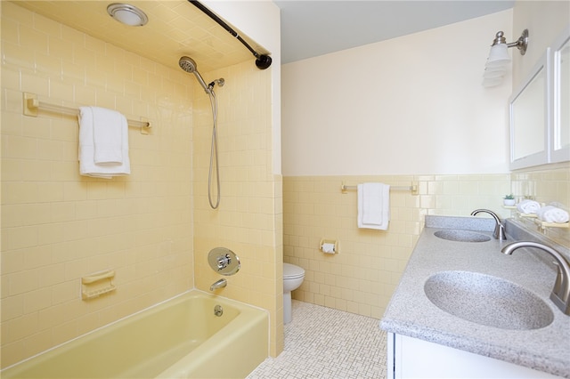 full bathroom with vanity, tile patterned flooring, tiled shower / bath combo, toilet, and tile walls